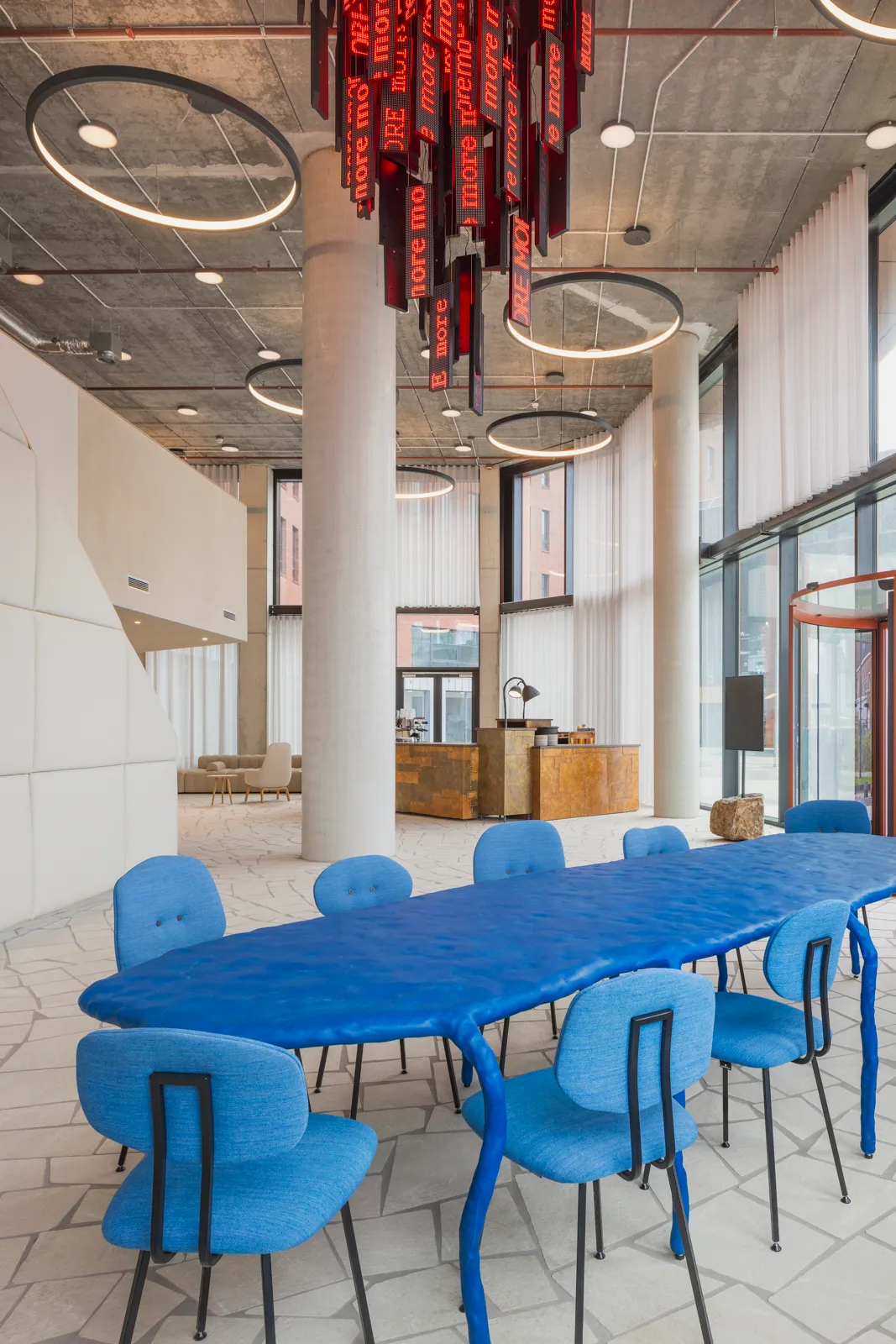 A blue sculptural Maarten Baas table beneath a red light installation in the Orato lobby