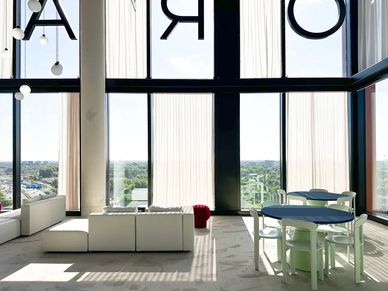 The double-height Sky Hub lounge with white sofas, pendant lights and a staircase
